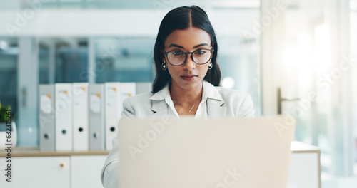 Business woman, glasses and working on laptop in office for planning, reading email and internet research in law firm. Indian lawyer, attorney and focus at computer to start legal analysis in company