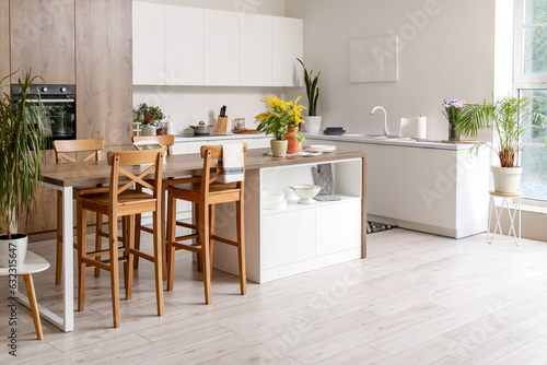 Interior of modern kitchen with white counters and island table
