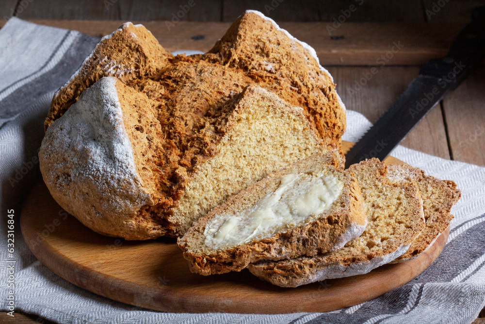 Traditional Irish soda bread made from whole grain and rye flour on a wooden table. Rustic style.