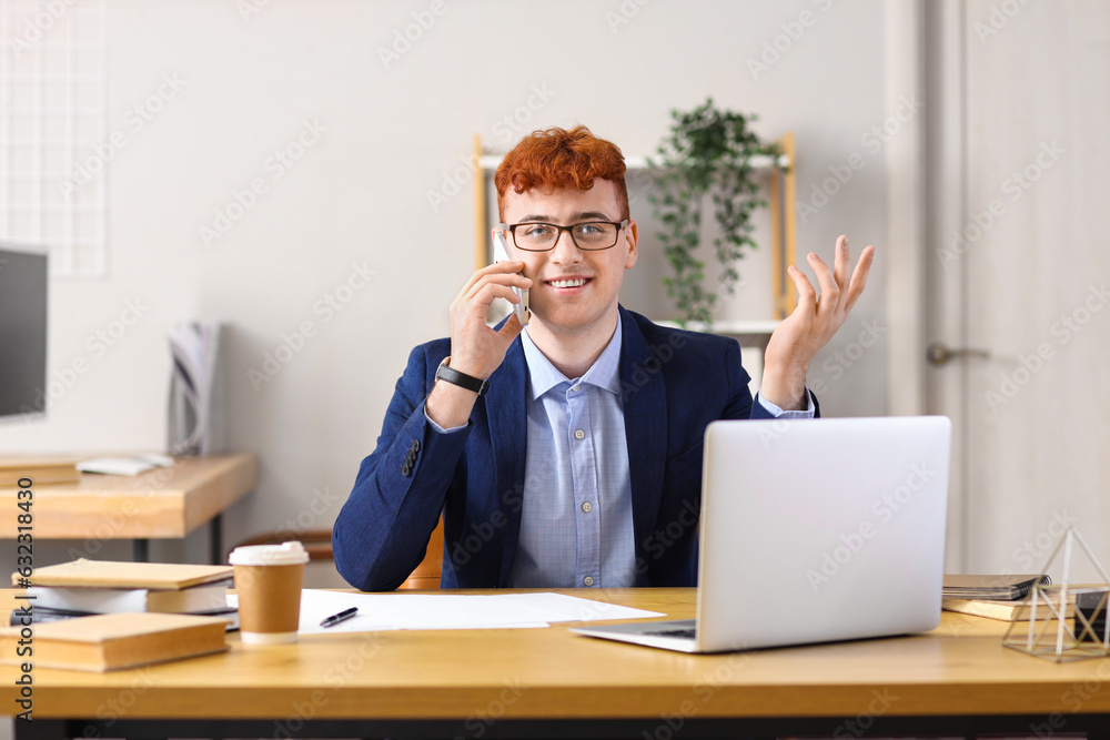 Young redhead businessman talking by mobile phone in office Young redhead businessman talking by mobile phone in office
