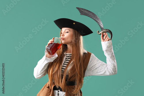 Beautiful female pirate with sword and rum on green background