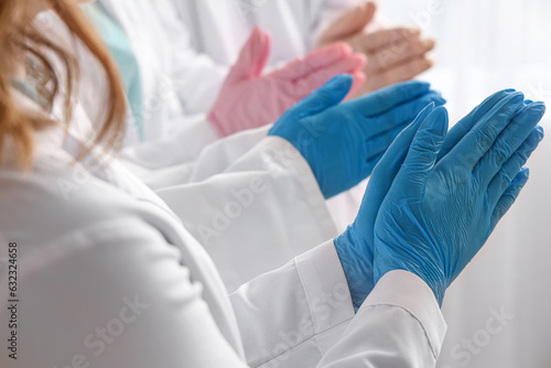 Doctors in medical gloves praying at clinic, closeup