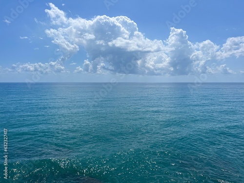 Blue sea shiny waves sky beautiful clouds. 