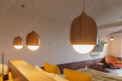 vue sur trois lampes suspendues au plafond en bois dans une pièce aux murs blancs avec la lumière allumée  photo