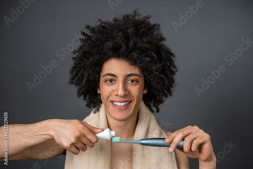 Young guy having morning procedures and brushing his teeth