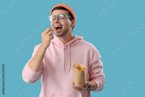 Young man eating french fri...