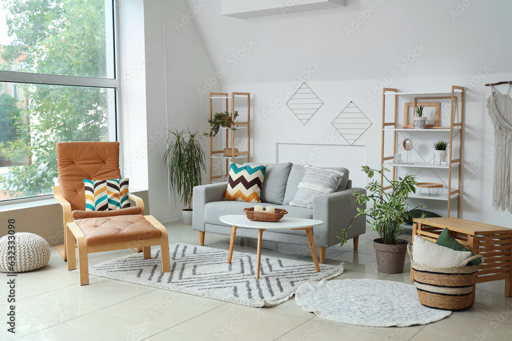 Fototapeta premium Interior of light living room with plants, sofa and armchair
