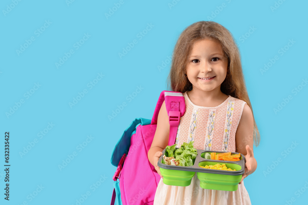 Happy little girl with backpack and lunchbox on blue background Happy little girl with backpack and lunchbox on blue background