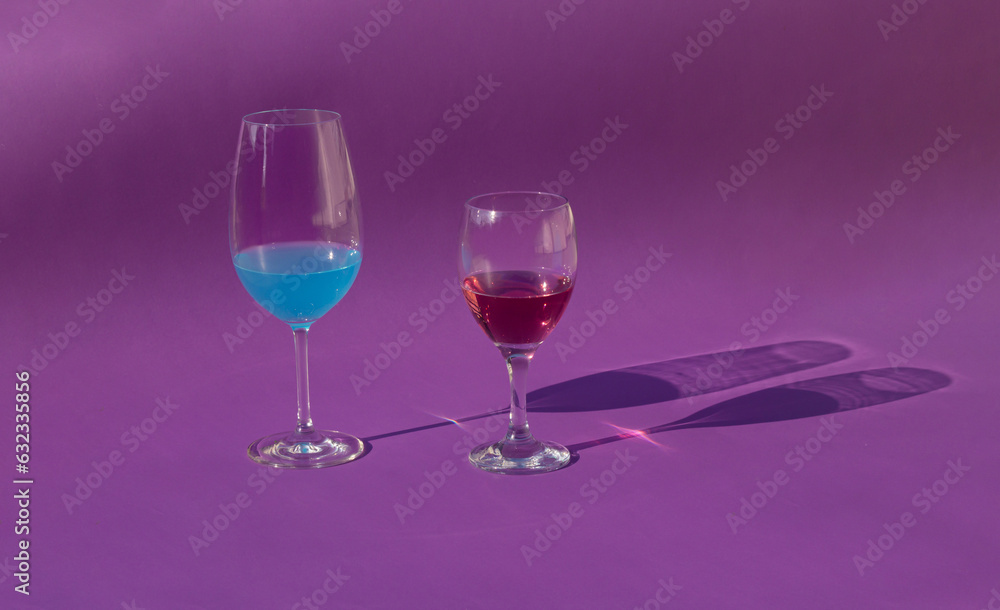 Minimal scene wine glass with red wine and blue cocktail on sunny day. Summer concept drinks and shadows on velvet background. Minimal scene wine glass with red wine and blue cocktail on sunny day. Summer concept drinks and shadows on velvet background.