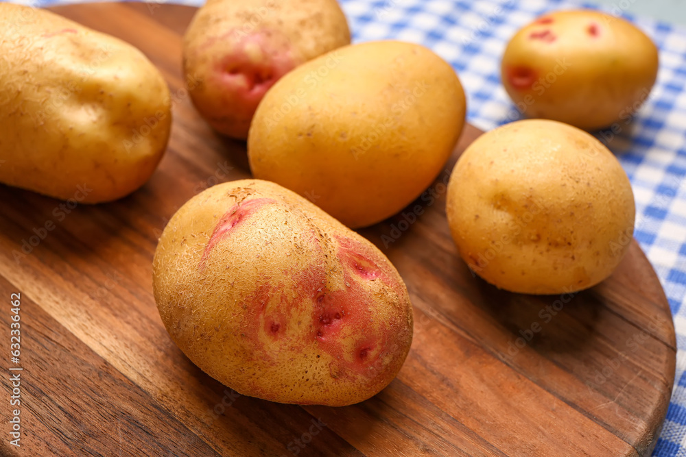 Wooden board with fresh raw potatoes on table, closeup Wooden board with fresh raw potatoes on table, closeup