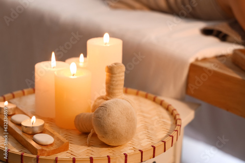 Burning candles and herbal bags on table in spa salon