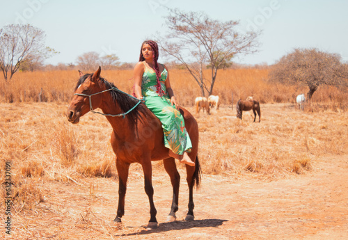 Mulher de vestido longo a cavalo em uma fazenda no interior da Bahia-Brasil, na estação de outono. © Maik Santozz