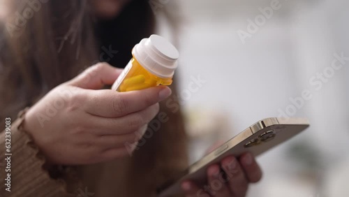 Hand of woman using smartphone for searching online information about prescription pill bottles