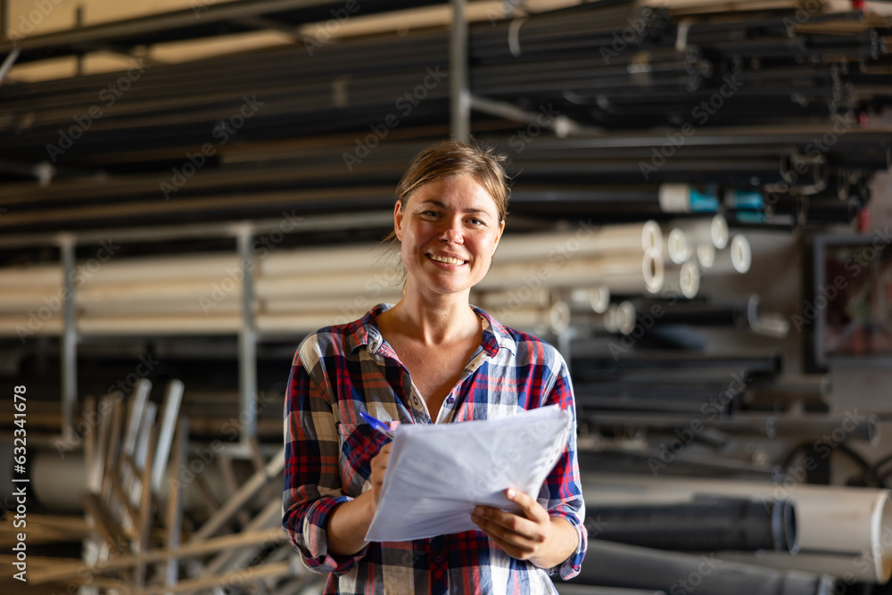 Obraz premium Portrait of positive caucasian woman working in warehouse, checking documentation.