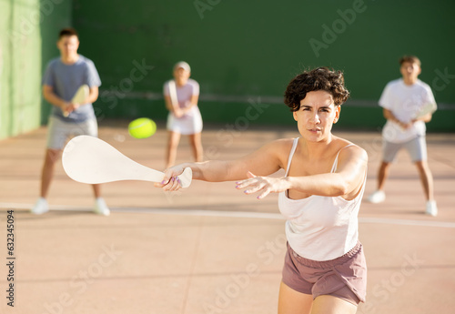 Latin woman playing Basque pelota on outdoor pelota court during training. Woman playing pelota speciality with wooden paleta. photo