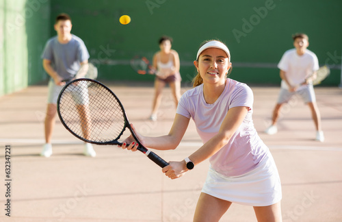 Sportive woman in shorts and t-shirt playing frontenis on outdoors court