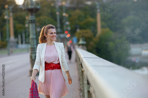 Photos happy trendy woman in pink dress and white jacket in city