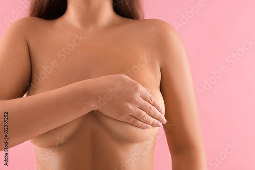 Naked woman covering her breast on pink background, closeup