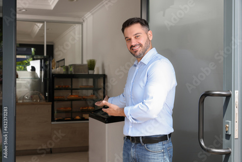 Fotografi Happy business owner inviting to come into his cafe