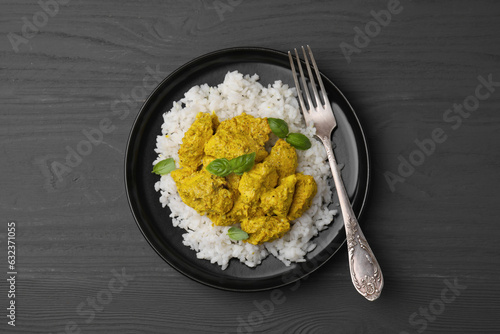 Delicious rice and chicken with curry sauce on grey wooden table, top view