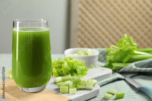 Glass of delicious celery juice and vegetables on wooden board, closeup. Space for text
