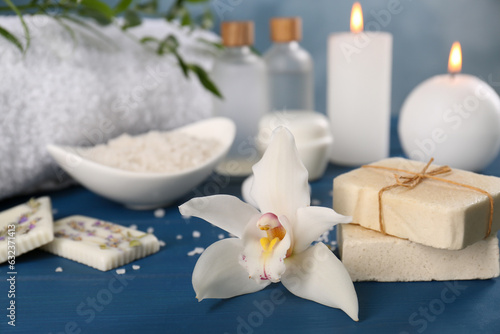 Soap bars and beautiful flower on blue wooden table, closeup with space for text. Retreat concept