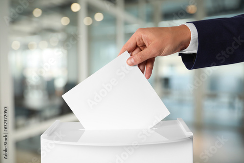 Man putting his vote into ballot box on blurred background, closeup