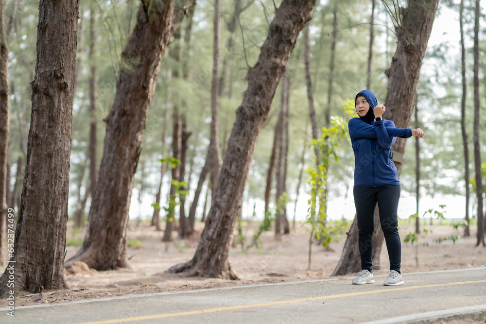 Fototapeta premium Happy cheerful Middle-aged Asian Muslim woman practicing exercise and stretching and enjoy jogging at the park close up with copy space. Modern muslim woman lifestyles and diversity concept.
