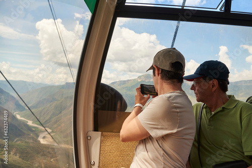 Senior hispanic man and his adult son enjoying a cable car ride over the Chicamocha Canyon, in Santander, Colombia photo