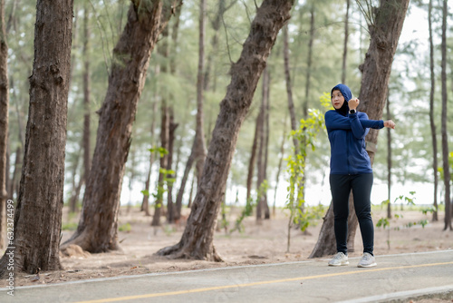 Happy cheerful Middle-aged Asian Muslim woman practicing exercise and stretching and enjoy jogging at the park close up with copy space. Modern muslim woman lifestyles and diversity concept. © maya1313