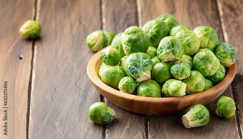 Green raw Brussels sprouts in a wooden bowl on a rustic wooden table, selective focus Green raw Brussels sprouts in a wooden bowl on a rustic wooden table, selective focus