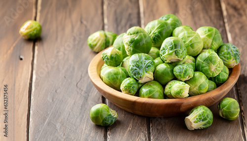 Green raw Brussels sprouts in a wooden bowl on a rustic wooden table, selective focus