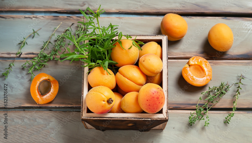 Fresh apricots in a small wooden box and herbs on rustic table, selective focus, top view Fresh apricots in a small wooden box and herbs on rustic table, selective focus, top view