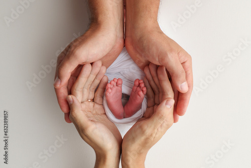 The palms of the father, the mother are holding the foot of the newborn baby on white background. Feet of the newborn on the palms of the parents. Photography of a child's toes, heels and feet