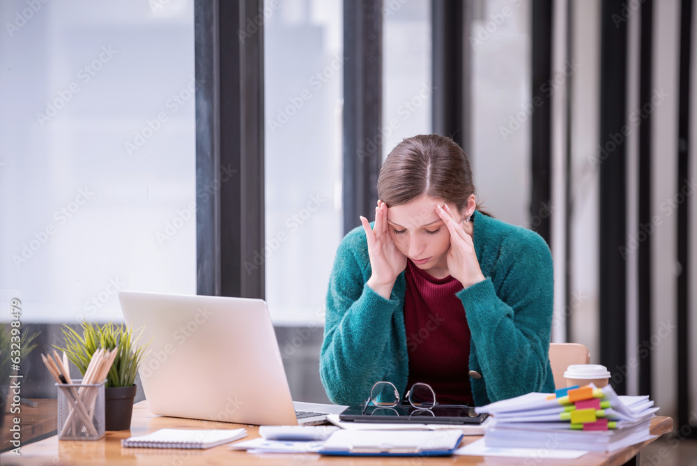 Businesswomen are stressed with work in front of a laptop and paper documents in the office. Businesswomen are stressed with work in front of a laptop and paper documents in the office.