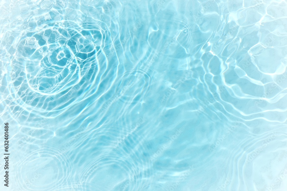 Obraz premium Blue water with ripples on the surface. Defocus blurred transparent blue colored clear calm water surface texture with splashes and bubbles. Water waves with shining pattern texture background.