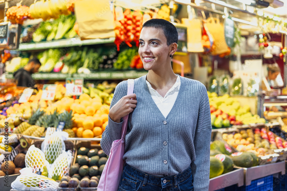 Obraz premium hispanic young woman with skinhead or short hair shopping vegetables on traditional market or grocery 