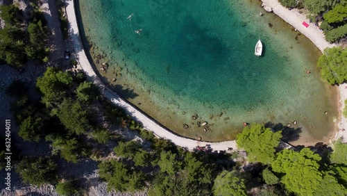 Aerial top down shot of Zavratnica Bay with sunken ship and tourist resting on beach during sunny day - Croatia, Europe photo