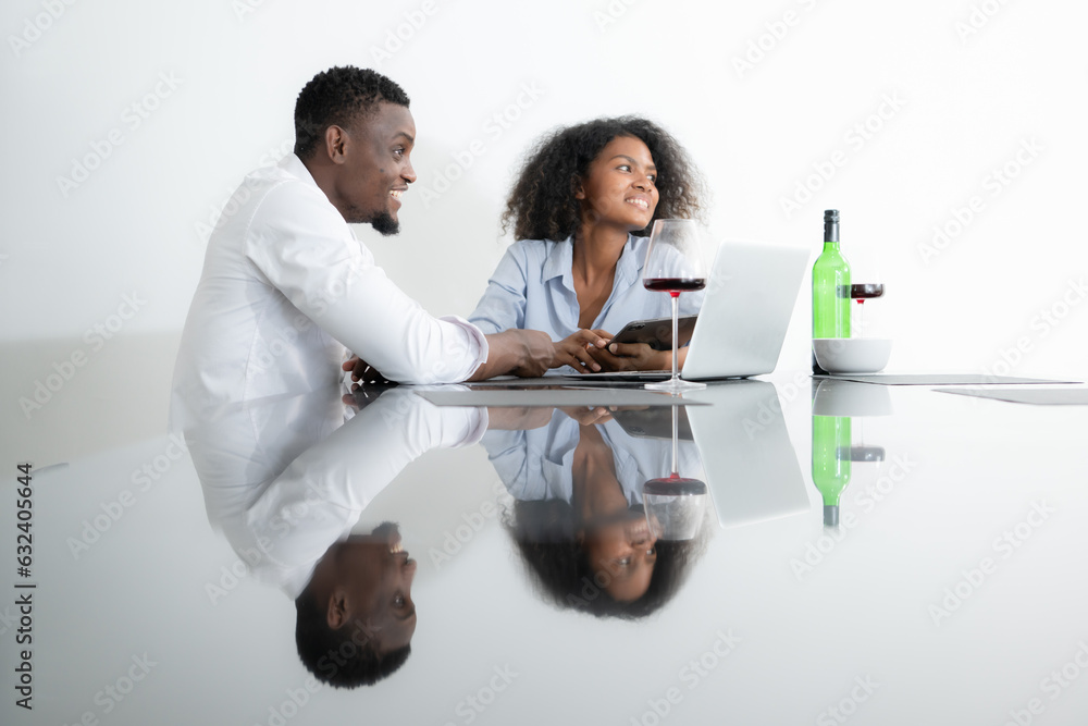 Both of young businesses drinking wine and use their laptops to share information with each other in their living room of house. Both of young businesses drinking wine and use their laptops to share information with each other in their living room of house.