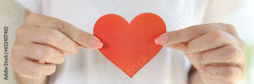 Female in white t-shirt holds red heart in her hands in front of her body. photo