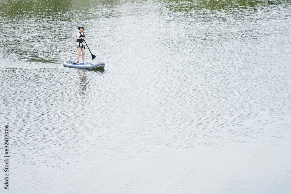 Naklejka premium 休日の川でサップを楽しむ日本人の女性
