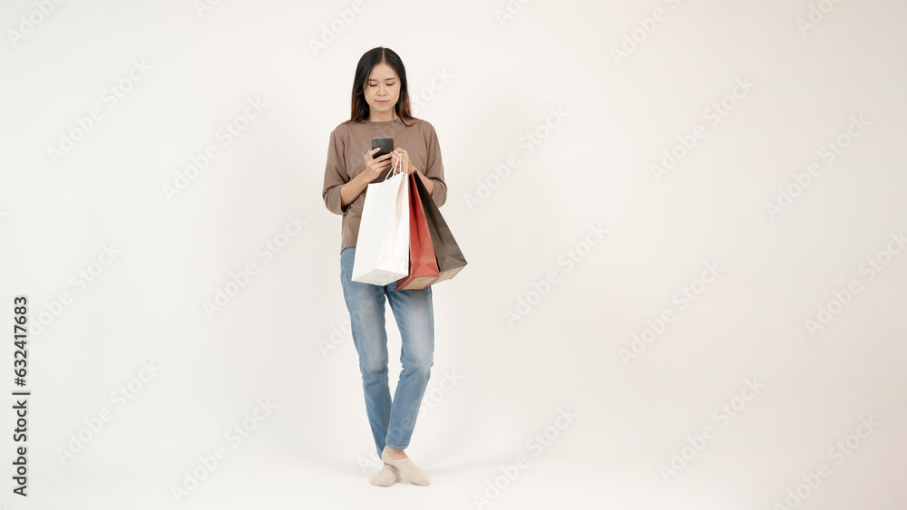 A beautiful Asian woman with her shopping bags is using her smartphone. isolated white background A beautiful Asian woman with her shopping bags is using her smartphone. isolated white background