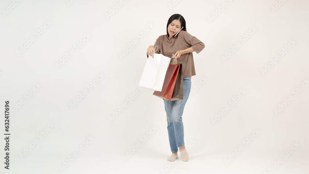 A busy Asian woman is talking on the phone while carrying her shopping bags. shopaholic A busy Asian woman is talking on the phone while carrying her shopping bags. shopaholic