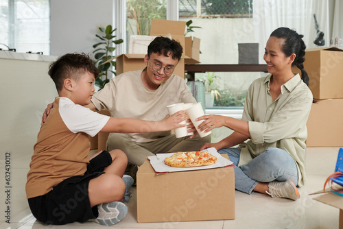 Fotografi Family toasting with glasses of soft drinks over improvised carboard table with