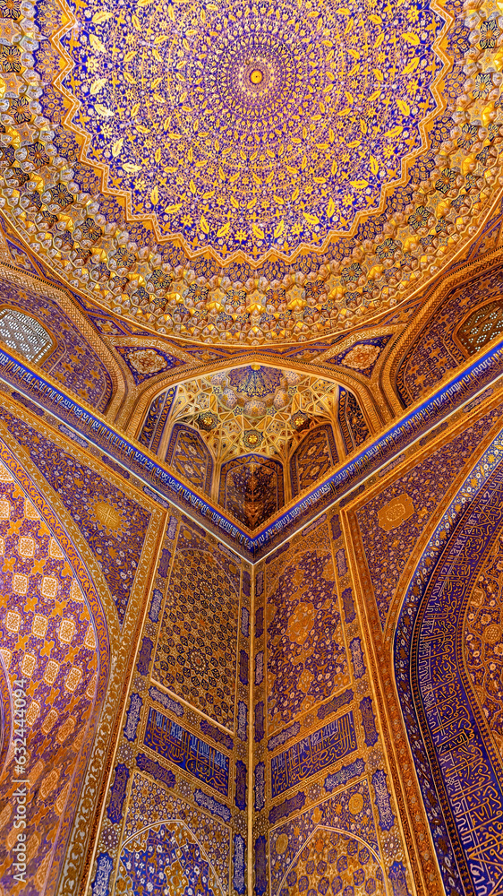 Painted gilded dome of Madrasa Tilya Kori (Registan complex). Arabic text of Koran (sacred book of muslims) used as part of ornament. Gold and blue, vertical. Samarkand, Uzbekistan