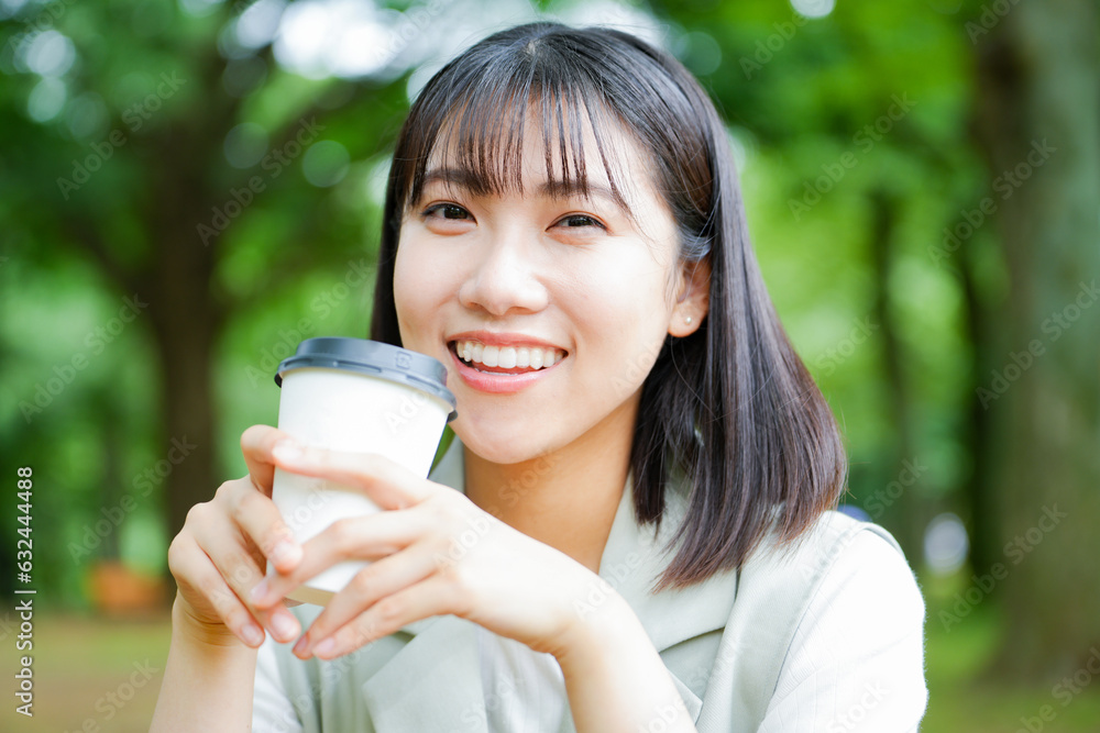 公園で飲み物を持つ女性 公園で飲み物を持つ女性