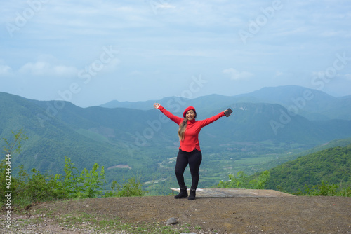 Smiling woman with positive attitude with landscape of hills behind her.