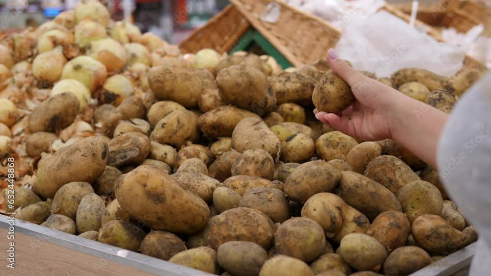 Close-up of a woman holding potatoes in a supermarket against the background of shelves with vegetables. Close-up of a woman holding potatoes in a supermarket against the background of shelves with vegetables.