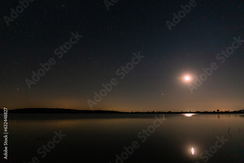 Tabuyo del Monte reservoir at night with stars and the moon before sunrise, Leon, Spain.