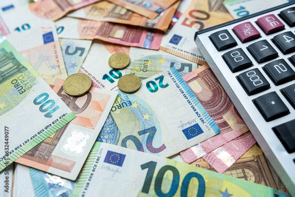 Euro coin and calculator above euro bills. Saving and finance concept Euro coin and calculator above euro bills. Saving and finance concept